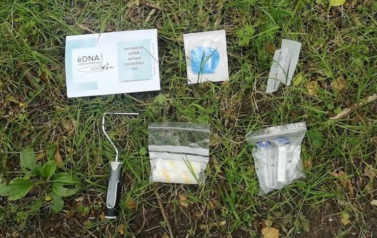 eDNA sample collection kit components on grass, including bags, vials, a brush, and instructions for terrestrial eDNA