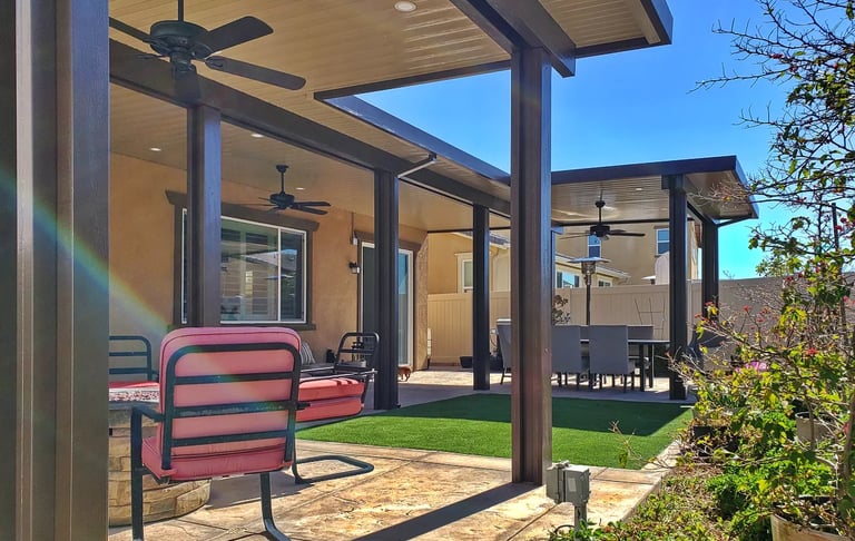 Large covered patio area with red chair, turf, and plants.