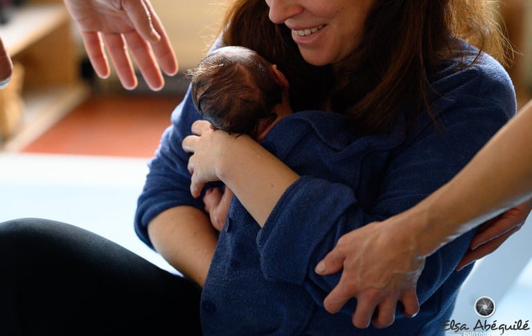 Une maman tenant son nouveau-né dans les bras après le Bain des Merveilles