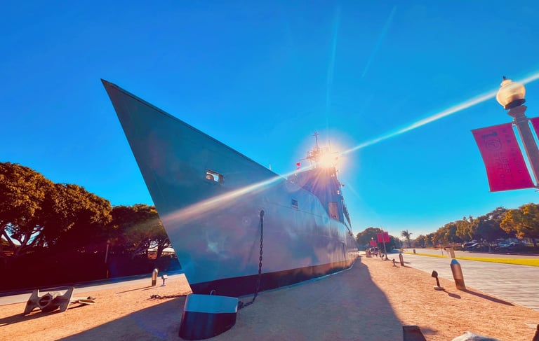 The USS Recruit landlocked ship model at Liberty Station in San Diego under a bright blue sky.