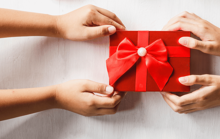 two hands holding a red gift box with a bow