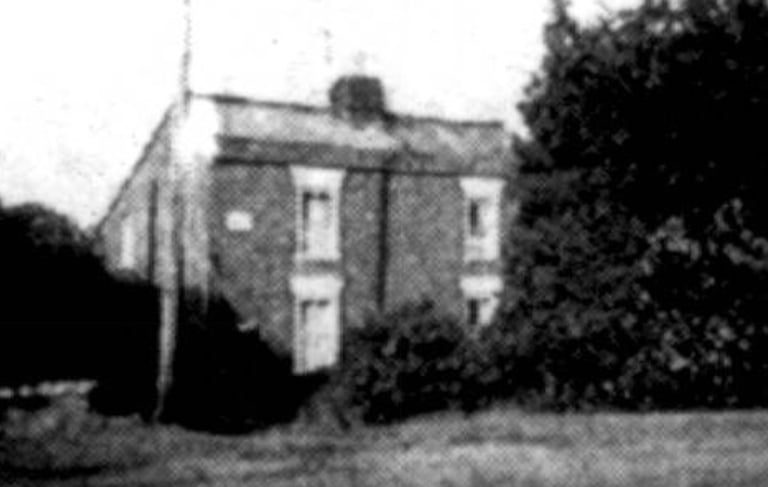 An old photograph of a pair of red brick cottages