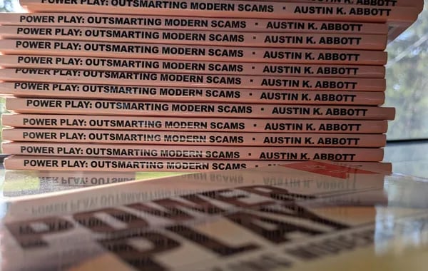 Stack of books titled Power Play: Outsmarting Modern Scams by Austin K. Abbott, arranged with their spines facing outward