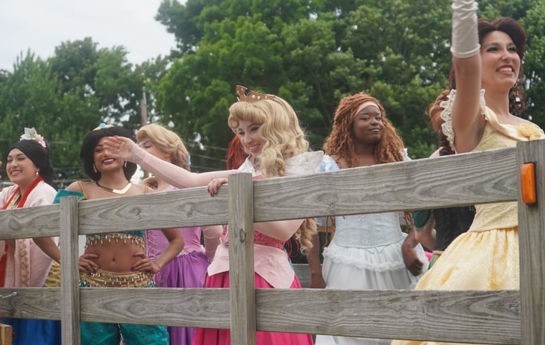 Princesses wave at guests during a parade