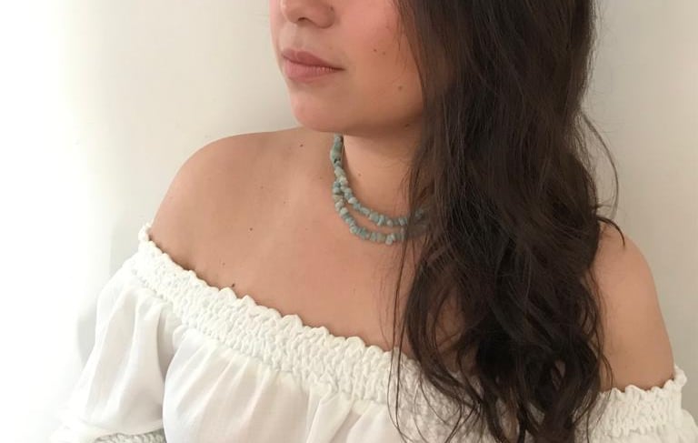 mulher com um colar feito de pequenas lascas de cristais verde esmeralda