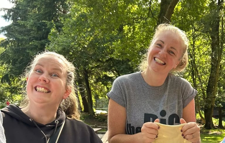 Two leaders smile at the camera while stretching dough for the 25th Allerton scout camp