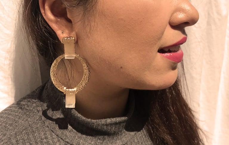 uma mulher com grandes brincos de argola de ouro com dois cristais nas extremidades
