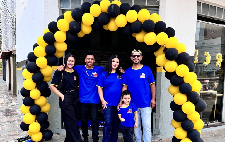 4 adultos e 1 criança com uniformes azuis, em frente a loja de baterias automotivas