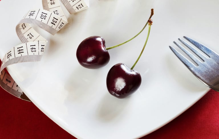 a fork and two cherries with a measuring tape on a plate