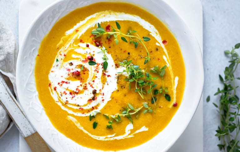 anti-inflammatory vegetable soup in white bowl with herbs and pomegranate seeds