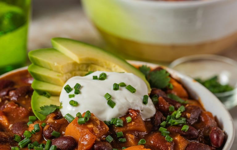 Bowl with vegan chili sin carne with beans, vegetables, vegan topping yogurt and avocado