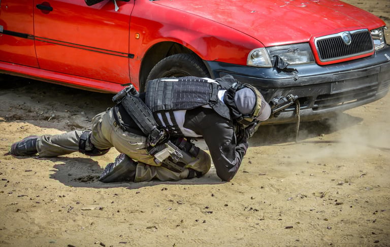 A tactical shooter in full gear aims a blue training pistol from behind a white car at a shooting range.