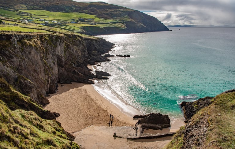 Turquoise ocean waves crashing on the sandy Dunmore Head beach along the rugged Dingle Peninsula coast in Ireland.