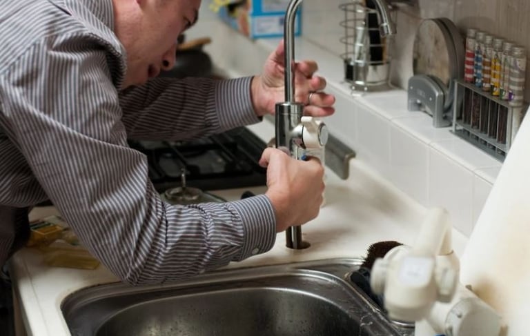 bc plumber a man in a shirt examining a tap