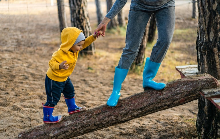 a woman in a yellow raincoat and blue boots is holding a child's