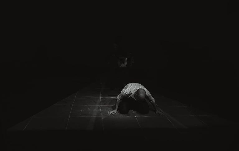 man knelling on the ground surrounded in darkness.  A light grid is displayed on the floor