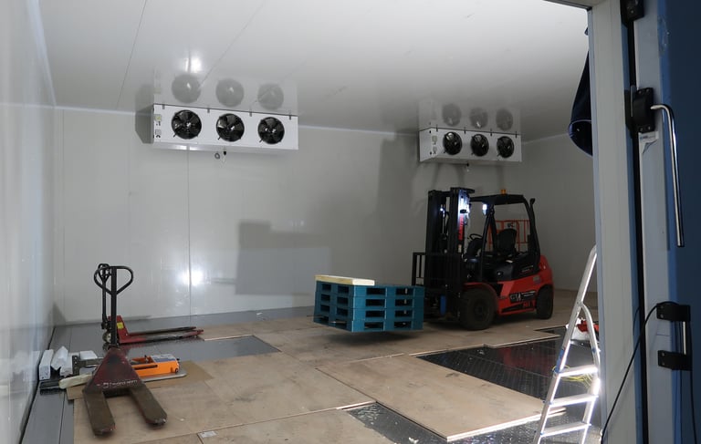 Team installing an evaporator unit with the help of a forklift inside a commercial cold storage faci