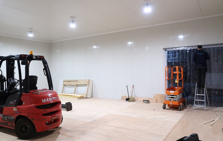 Interior of a spacious freezer warehouse showing both a forklift and scissor lift, illustrating the 