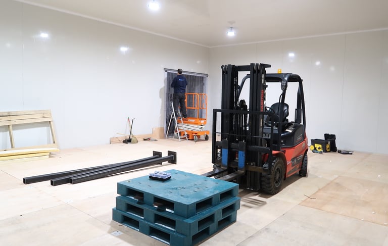 Perspective shot of a cold storage facility with heavy machinery inside, emphasizing the size and in