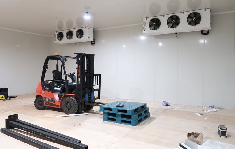 Wide view of a giant commercial freezer room with a forklift inside, highlighting the massive scale 