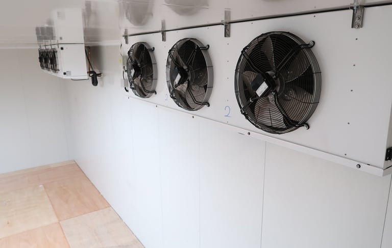 Two large industrial evaporators mounted on the ceiling of a giant commercial freezer room for cold 
