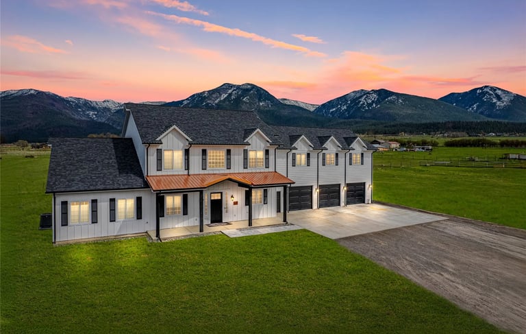 a large house with a large lawn and mountains in the background