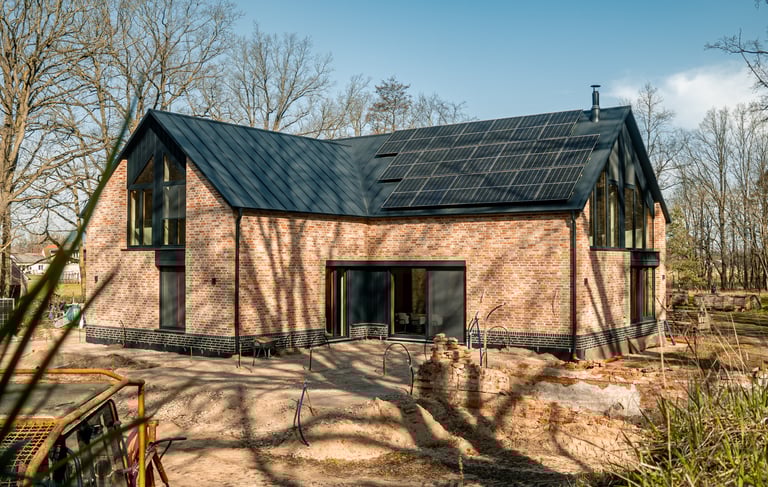 Modernes Einfamilienhaus mit Klinkerfassade, großen Glasflächen und Solarpaneelen auf dem Dach