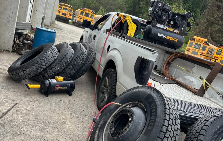 Mobile tire service truck with an air compressor and large school bus tires for roadside repair.