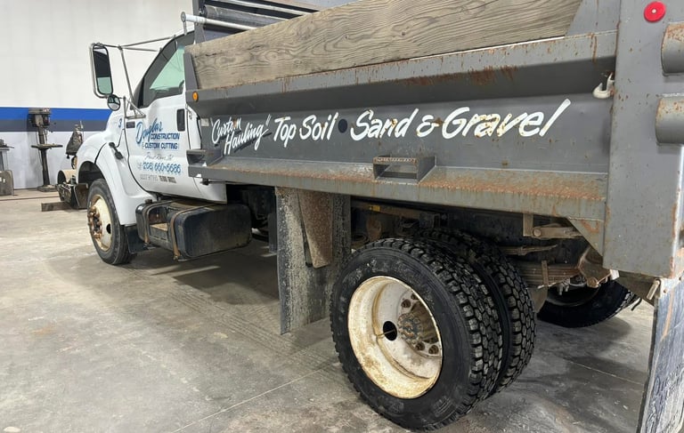 White custom hauling dump truck for top soil, sand, and gravel parked in a commercial garage.