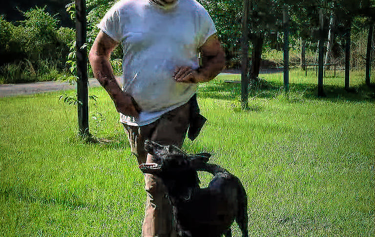 a man standing in the grass with a dog