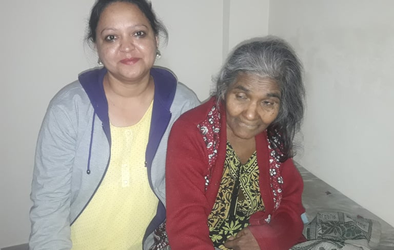 a woman sitting on a bed with an old woman