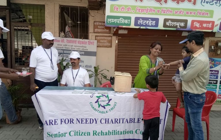 a group of men, woman, and children are standing in front of a table with a sign doing vaccination