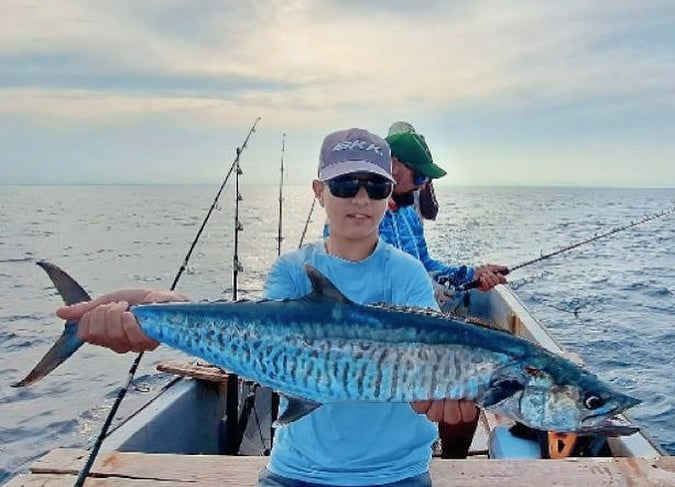 A happy beginner angler holding a fish on a boat in Zanzibar