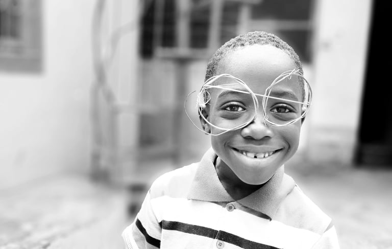 a young boy wearing home-made glasses and a striped shirt