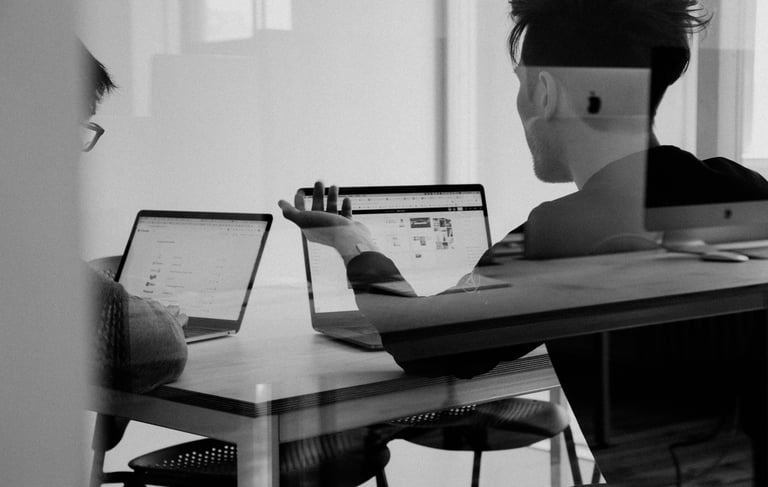 a man sitting at a table with a laptop and listening to conference call