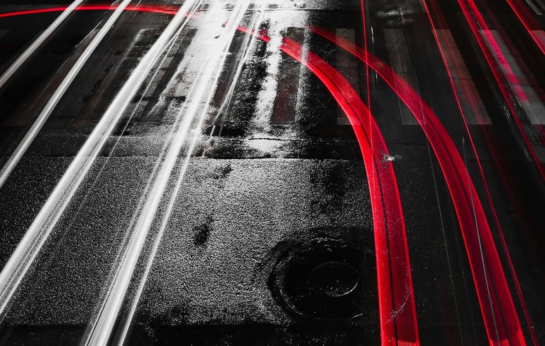 a black and white photo of a city street with red and white light streaks