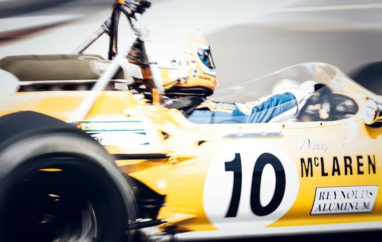 Vintage yellow McLaren Formula 1 race car with number 10 speeding on Monaco track with motion blur.