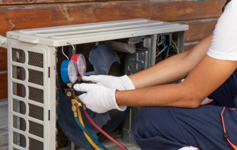 a man in a white shirt and gloves is fixing a heat pump