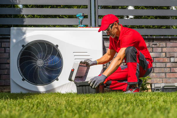 a man in a red shirt and a red hat is working on a white refrigerator