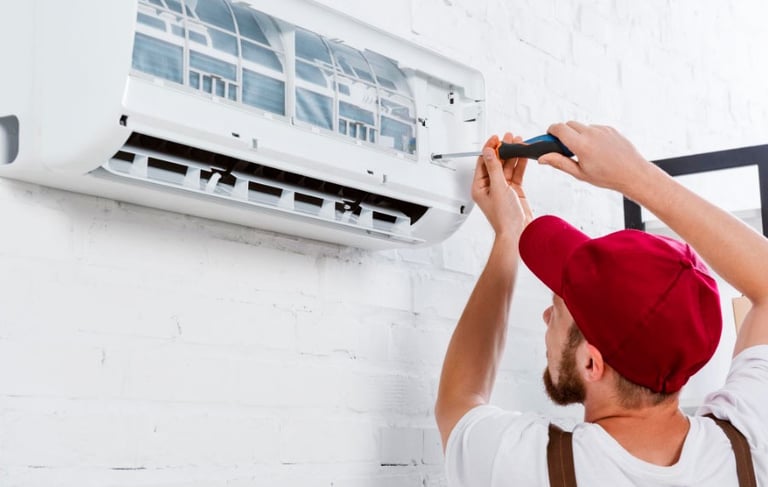 a man in a red hat is fixing a air conditioner
