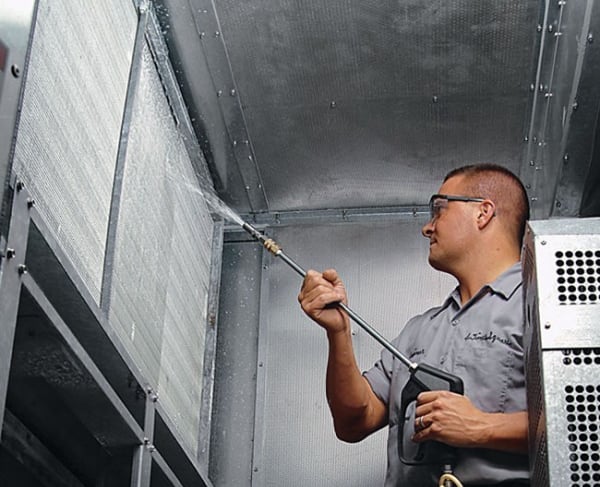 a man in a gray shirt is spraying a cell phone