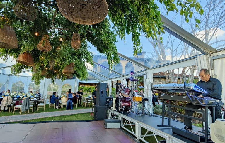 pianista sobre escenario bajo una tolda transparente con decoracion floral colgante