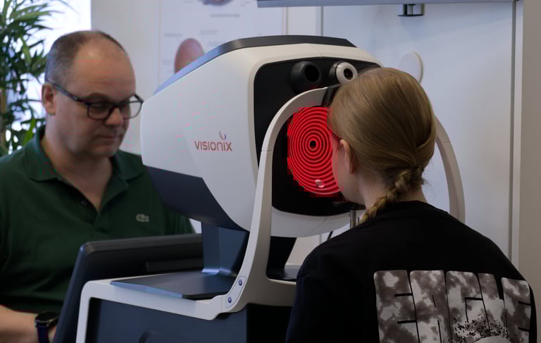 Patient undergoing an eye exam with a Visionix diagnostic scanner at an optometrist.