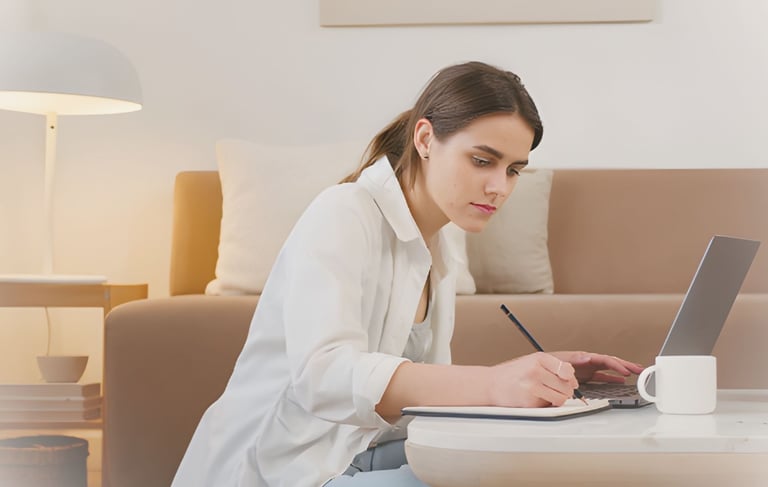 a woman sitting at a table with a laptop and a cup of coffee