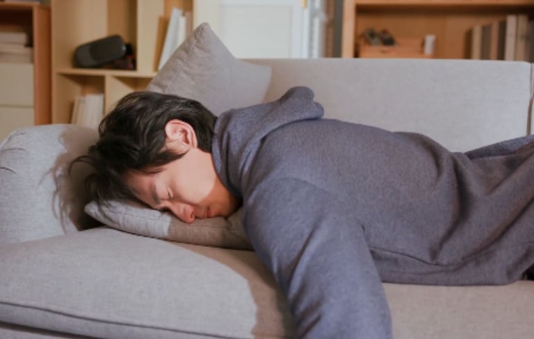 a man is resting on a couch with face in a pillow