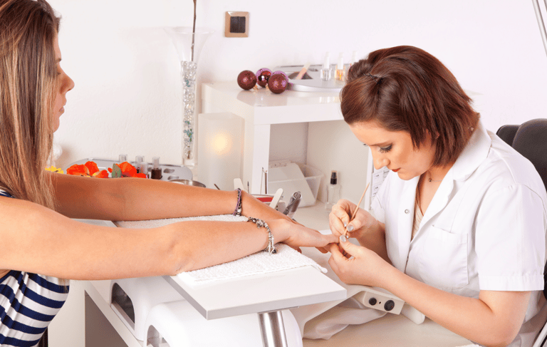 Nageldesigner mach Nägel einer Kundin