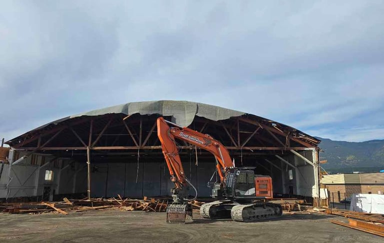 excavator in front of an demolition project of an arena