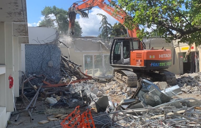an excavator crushing a building made of concrete