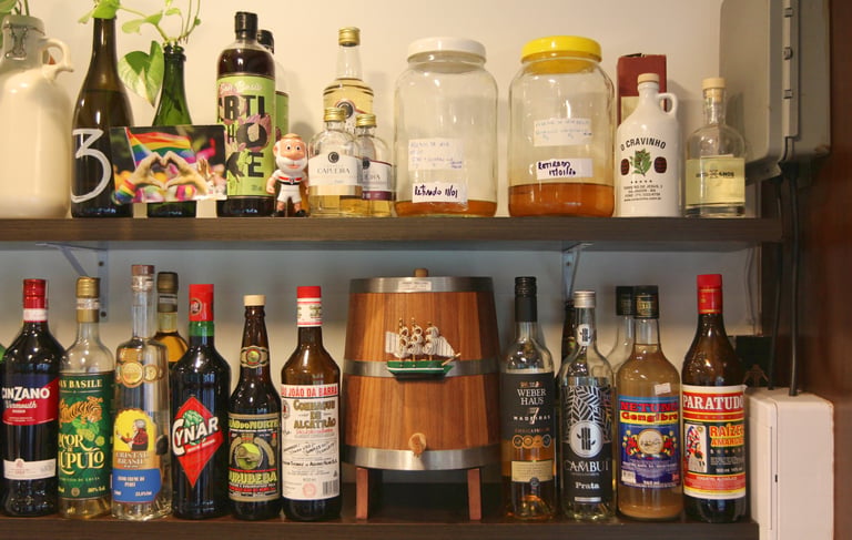 Rustic home bar shelf featuring a wooden barrel and various bottles of Brazilian cachaça and spirits.