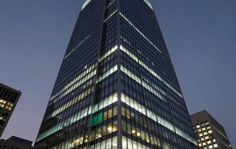 A sophisticated, low-angle photograph of a modern glass-and-steel skyscraper in a major North American tech hub at dusk. The building is illuminated with soft white and cyan lighting against a dark blue-gray night sky. The scene conveys technological power and corporate reliability.